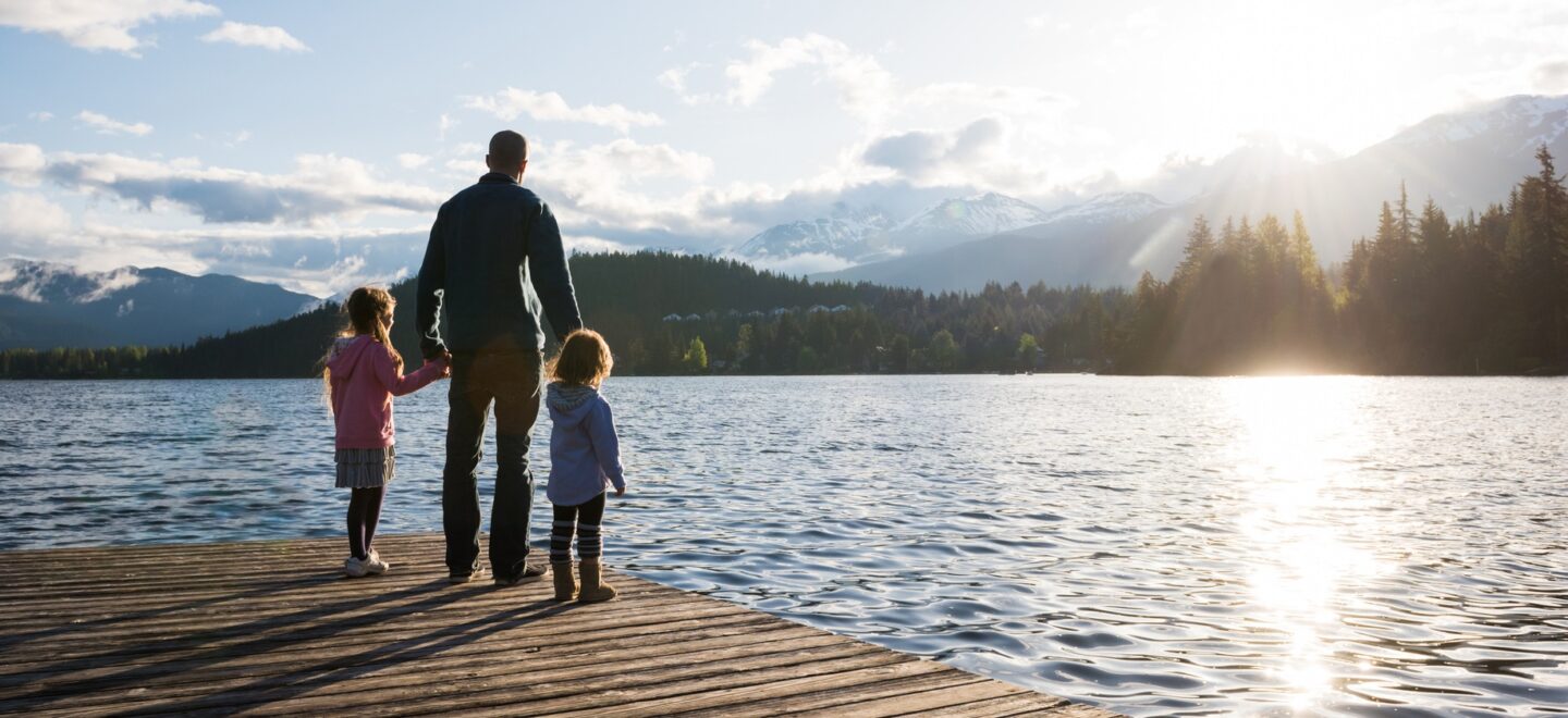 parent and 2 children standing on dock at lake