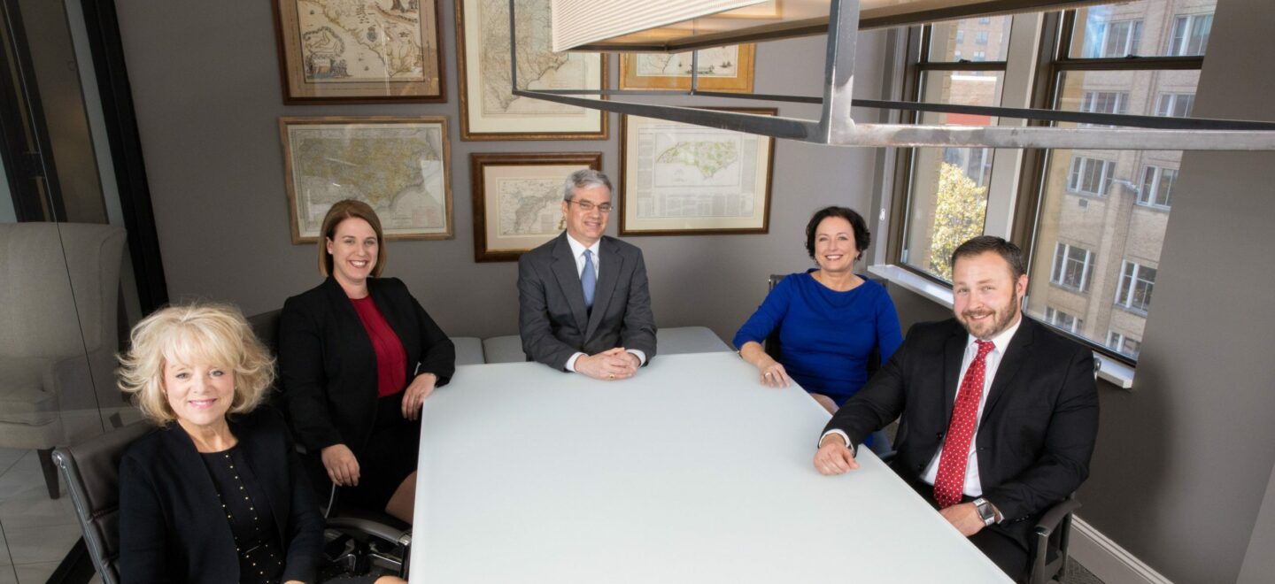 five formally dressed business people at a table