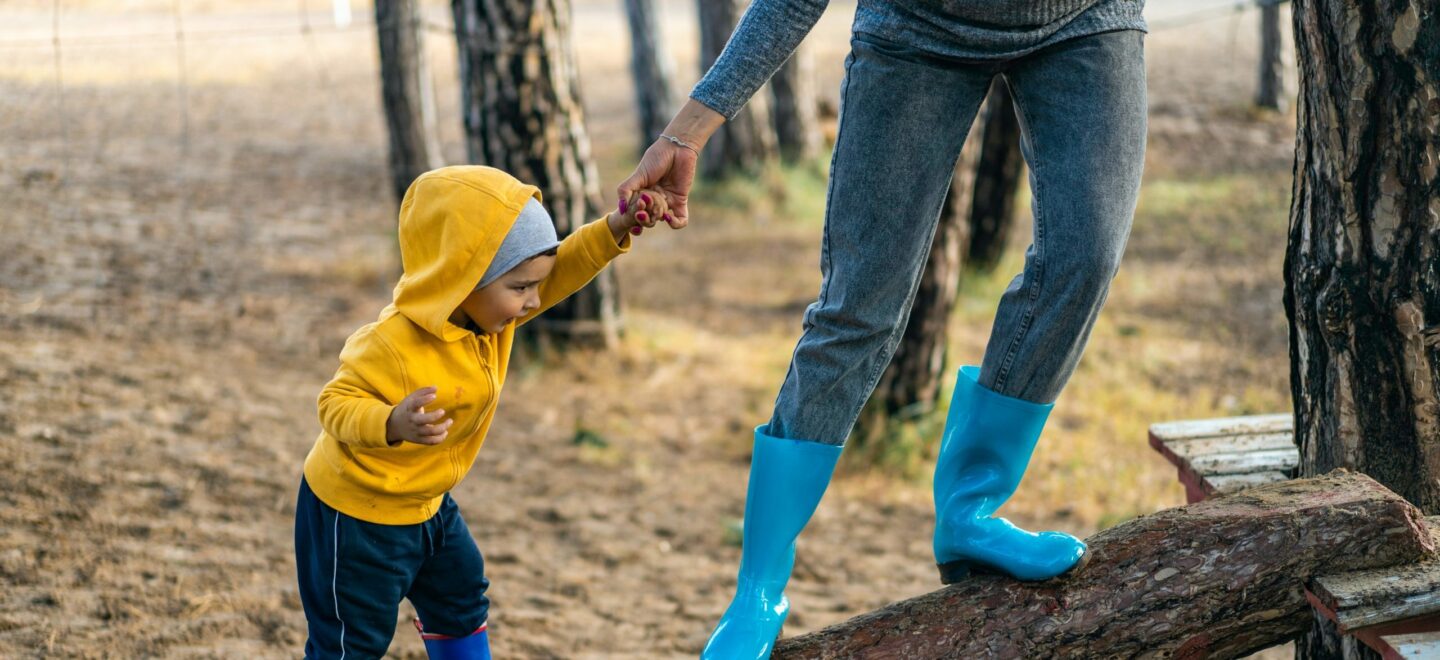 child holding hand and walking up fallen tree